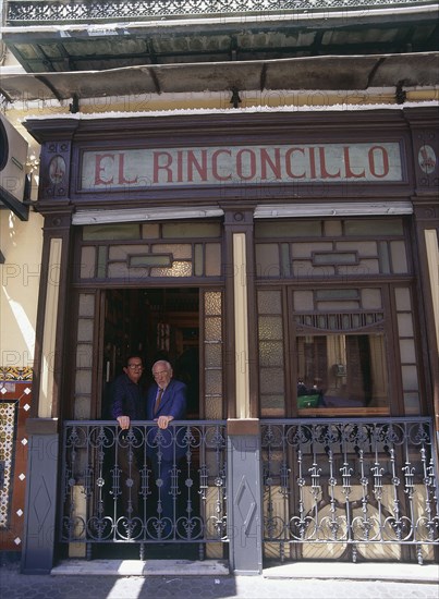 SPAIN, Andalucia, Seville, Macarena District El Rinconcillo where Tapas originated with two men standing at a window