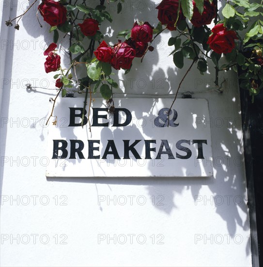 ARCHITECTURE, Hotels, Bed and Breakfast, Detail of sign advertising bed and breakfast accommodation over-hung with roses.