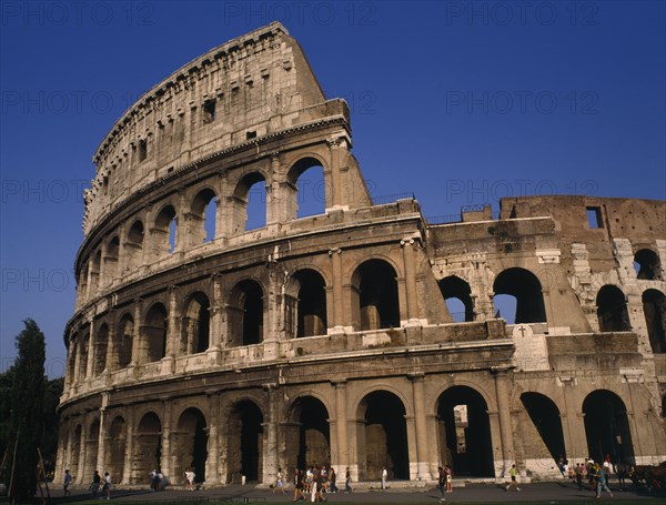 ITALY, Lazio, Rome, Colosseum view from south with visitors gathered around base.