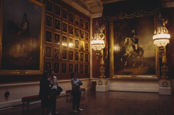 RUSSIA, St Petersburg, "The Hermitage Museum interior, room hung with portaits, three people look at paintings "