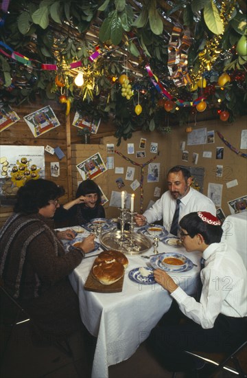 SOCIETY, Religion, Judaism, England.  Jewish family eating a meal in a Sukka during the Sukkot Festival.