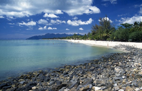 MALAYSIA, Langkawi, Kedah, Pantai Cenang beach looking towards Gunung Mat Cincang with a stoney beach in the foreground
