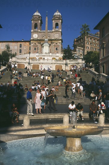 ITALY, Lazio, Rome, Piazza di Spagna.  Fountain in the foreground with people on the Spanish Steps behind.