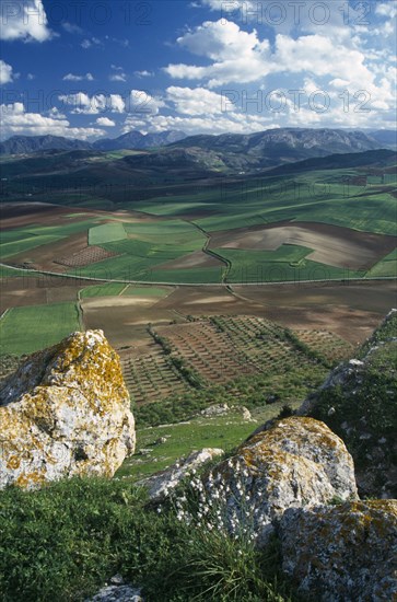 SPAIN, Andalucia, Malaga Province, "View over plain towards distant hills.  Large, lichen covered boulders in the foreground.  "