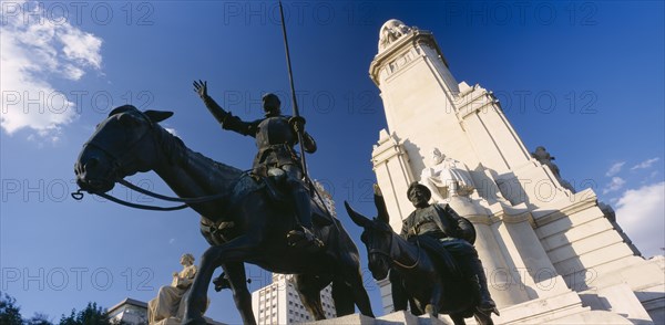SPAIN, Madrid State, Madrid, "Plaza de Espana.  Angled view of the statues of Miguel de Cervantes with Don Quixote on his horse and Sancho Panza on a donkey  in the foreground, seen from below."