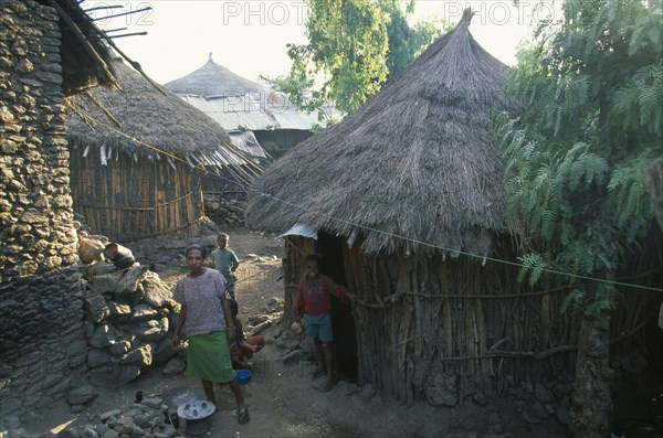 ETHIOPIA, Wolo Province, Lalibela, Young woman and children outside circular wooden house with thatched roof.