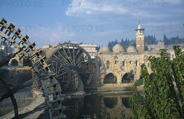 SYRIA, Central, Hama, Wooden norias or waterwheels on the Orontes river and the Al-Nuri Mosque dating from 1172 and built of limestone and basalt.