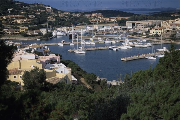 ITALY, Sardinia, Costa Smeralda, Porto Cervo harbour. View down over buildings and harbour with white boats.