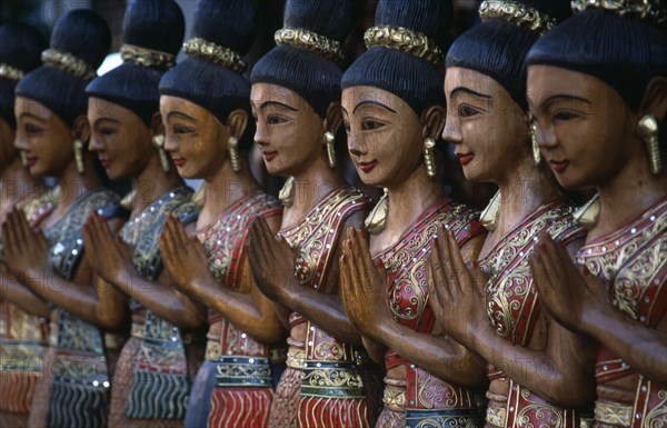 THAILAND, North, Chiang Mai, Loi Kroh. Traditional wooden carvings of women outside a crafts shop