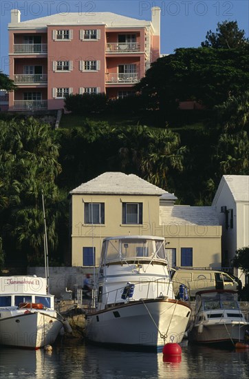BERMUDA, Flatts Village, Pink building with white shutters and balconies overlooking boats moored in the water below.