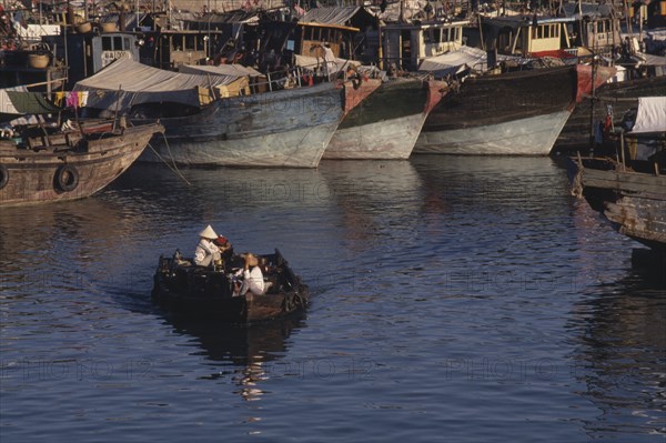 CHINA, Hainan Island , Sanya, People in a small motor boat passing in front of fishing boats moored in the harbour