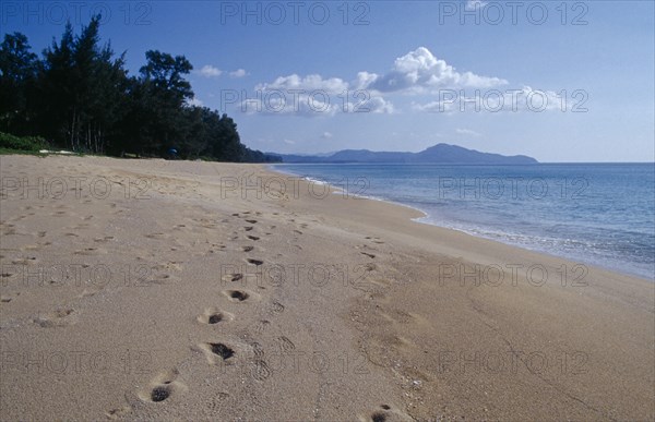 THAILAND, Phuket , Mai Khao Beach, View north west along empty sandy beach with lines of footprints in the foreground