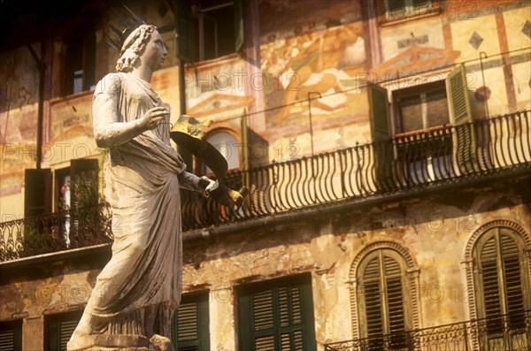 ITALY, Veneto, Verona, "Piazza della Erbe.  Detail of the Fountain of Madonna, statue of female figure in crown in front of building with painted facade, green window shutters and balcony."