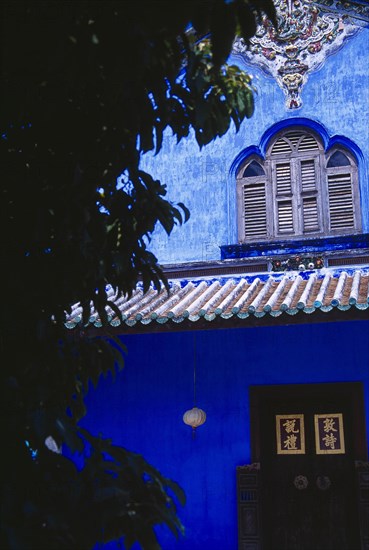 MALAYSIA, Penang, Georgetown, "Cheong Fatt Tze Mansion.  Restored Chinese merchants house.  Exterior detail with blue painted walls, wooden window shutters and overhanging roof. "