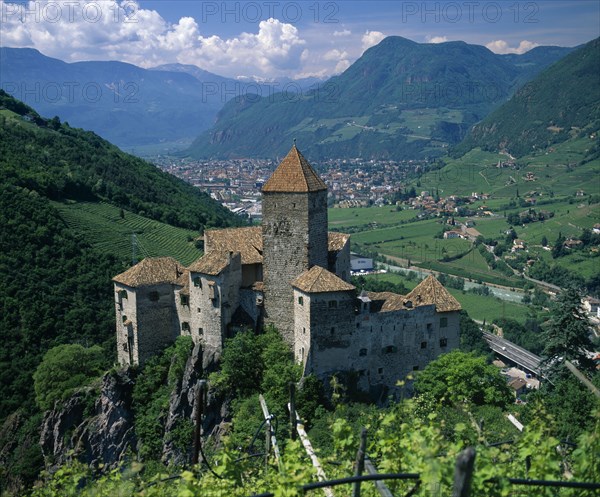 ITALY, Trentino Alto Adige, Bolzano, View over distant mountain village Karneid castle in foreground Summer time