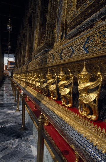 THAILAND, Bangkok, Grand Palace with Perspective of golden figures at side of Temple of Emerald Buddha.