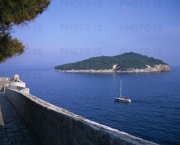 CROATIA, Dalmatia, Dubrovnik, Boat sailing between the City Walls or Gradske Zidine and Kolocep Island