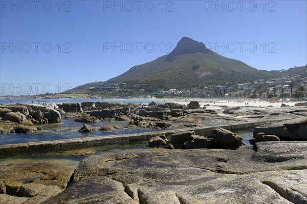 SOUTH AFRICA, Western Cape, Cape Town, Caps Bay. View over rocky coastal area with beach and mountain beyond
