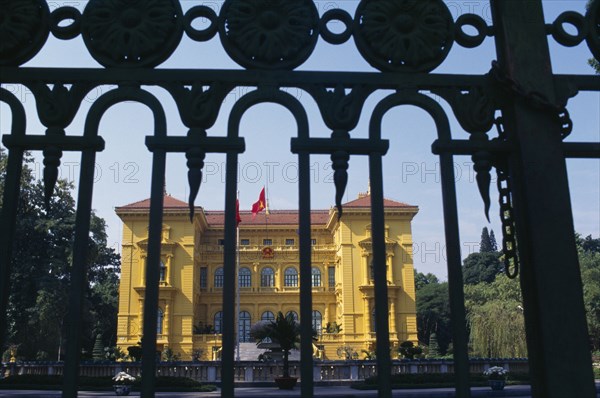 VIETNAM, North, Hanoi, The Presidential Palace yellow painted exterior facade seen through metal gate railings.