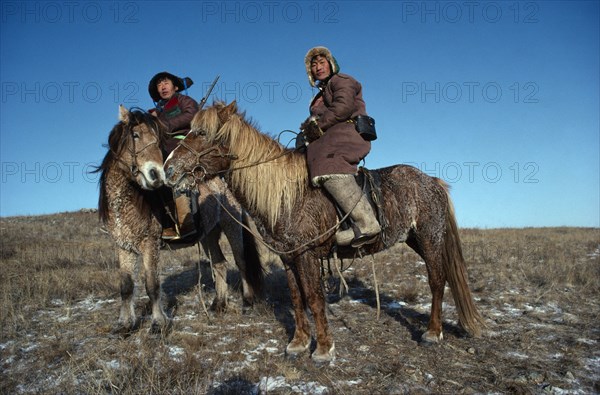 MONGOLIA, Transport, Two wolf hunters on Mountredon ponies in the autumn with frost on the ground