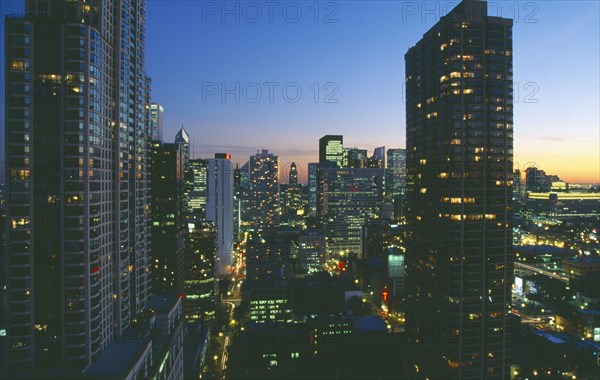 USA, Illinois, Chicago, Cityscape at night looking south down Rush and Wabash streets in the Near North of downtown Chicago.  Chicago Place in left of foreground.