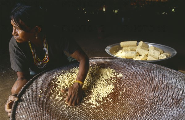 COLOMBIA, Amazonas, Santa Isabel, Macuna woman sieving manioc that has previously been grated washed and pressed.