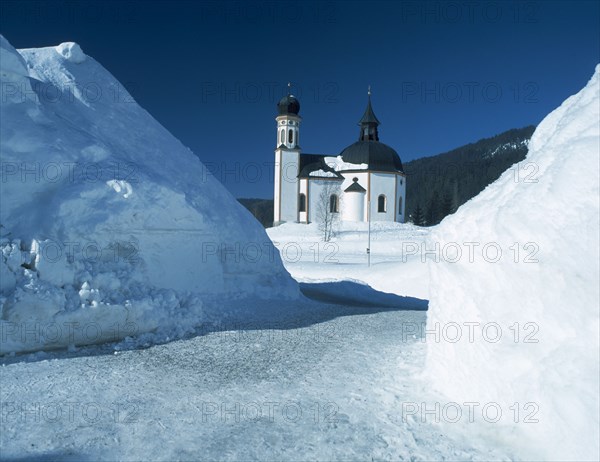 AUSTRIA, Tyrol, Seefeld Village, View through snowy mounds toward the Seekirchl church on the edge of the village