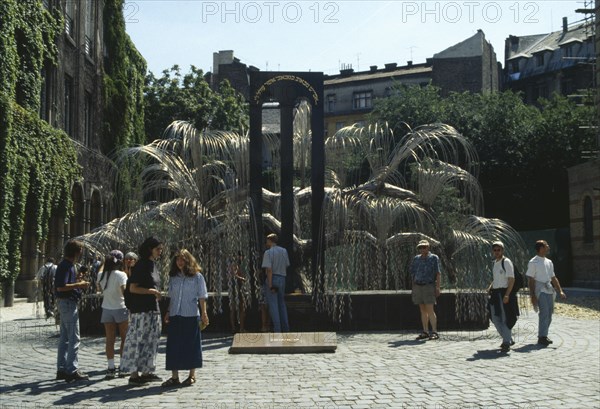 HUNGARY, Budapest, Dohany Street Synagogue.  Visitors beside Holocaust memorial designed by Imre Vaga in form of a weeping willow tree.
