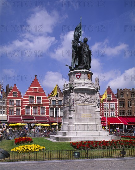 BELGIUM, West Flanders, Bruges, Statue of Jan Breydel and Pieter de Coninck in the market place. Row of cafes and restaurants behind.