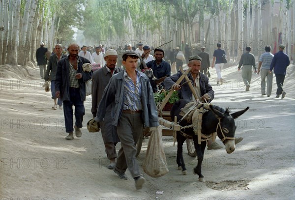 CHINA, Xinjiang, Kashgar, Men and donkey pulled cart heading along the roadside to market