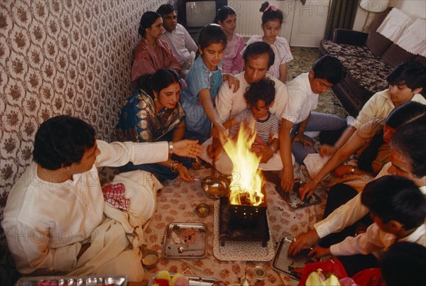 ENGLAND, Religion, Hindu, Hindu family participating in head shaving ceremony of young son in domestic interior.