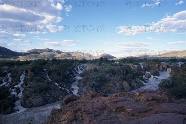 NAMIBIA, Epupa Falls, Water gushing through rocky cliffs into fast flowing river.