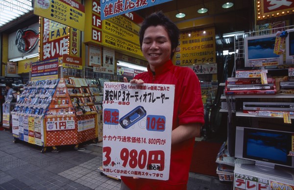 JAPAN, Honshu, Tokyo, Akihabara Electronics District. Vendor holding poster outside his electrical store