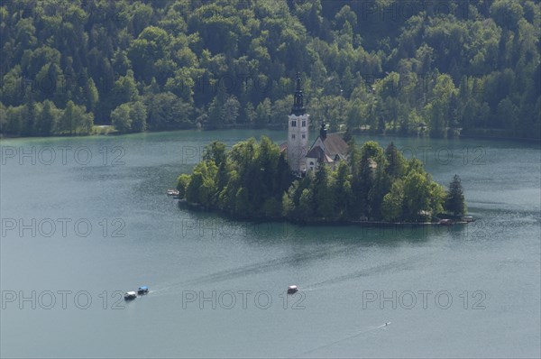 SLOVENIA, Lake Bled, Bled Island seen from the ramparts of the castle with traditional gondolas or rowing boats taking visitors across the lake