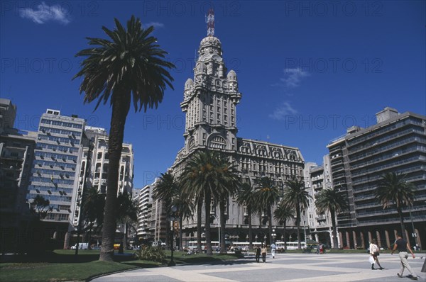URUGUAY, Montevideo, City scene with tree lined square in foreground and mix of old and new buildings behind.