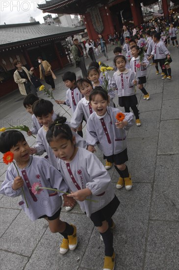 JAPAN, Honshu, Tokyo, "Asakusa. 4 year old nursery students from Senso-ji Dembo-in Nursery, carrying flowers to present to Buddha as part of his birthday celebrations, accopamied by Buddhist monk"