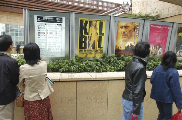 JAPAN, Tokyo, Roppongi, Roppongi Ark Hills Ark Tower. Japanese looking at poster for foreign film Kill Bill
