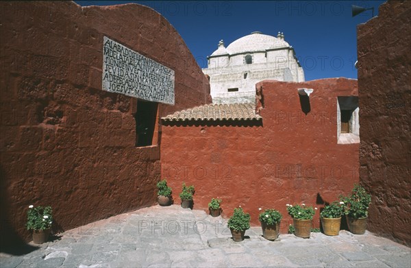 PERU, Arequipa, Alleyway with brightly coloured buildings and the white roof of the Monasterio de Santa Catalina beyond