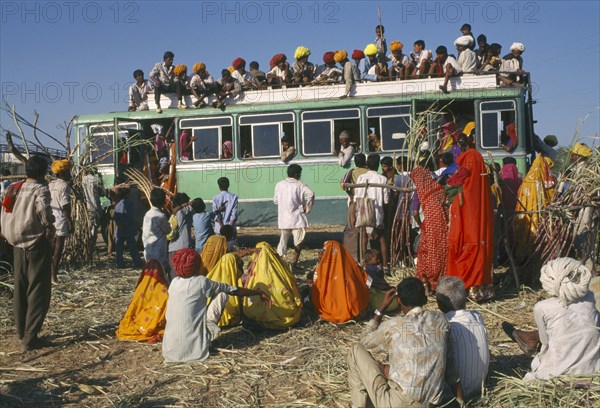 INDIA, Rajasthan, Pushkar, Over crowded bus with passengers on the roof