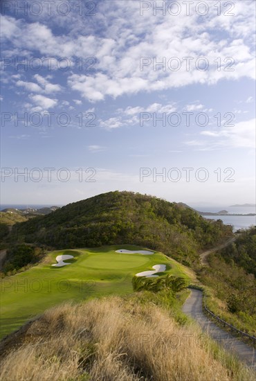 WEST INDIES, St Vincent & The Grenadines, Canouan, Raffles Resort showing the 12th green on the Trump International Golf course with the southern Grenadine islands in the distance