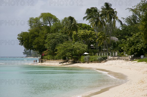 WEST INDIES, Barbados, St Peter, People walking along beach at Gibbes Bay past one of the exclusive houses