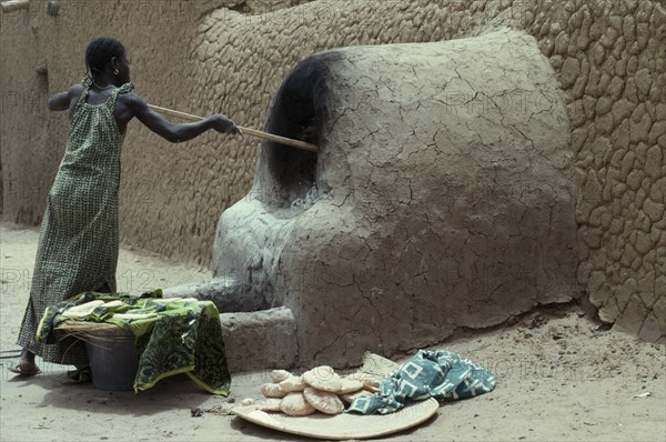 MALI, Timbuctu, "Woman making bread, cooking outside using mud brick oven."