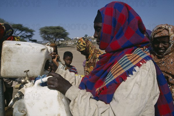 ETHIOPIA, Jijiga, Woman filling water containers at standpipe in Somali camp.