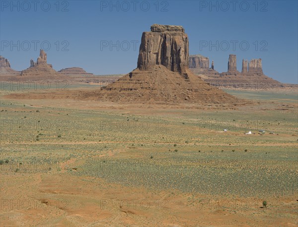 USA, Arizona, Monument Valley, View across the valley towards rock formations and a Indian settlement on the desert ground below