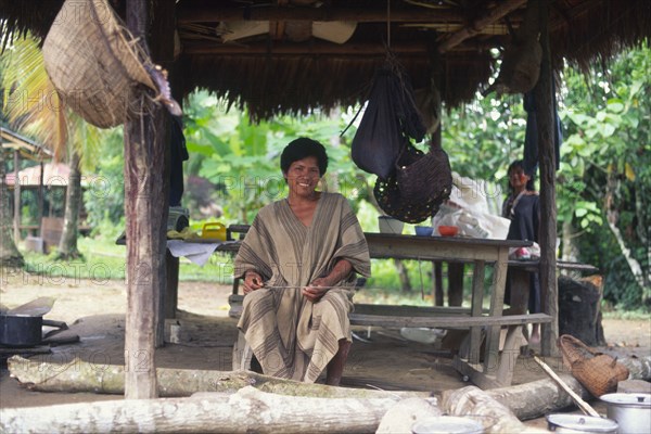 PERU, Nuevo Mundo, Camisea, Machiguenga indian man under a shelter and surrounded by traditional domestic items.