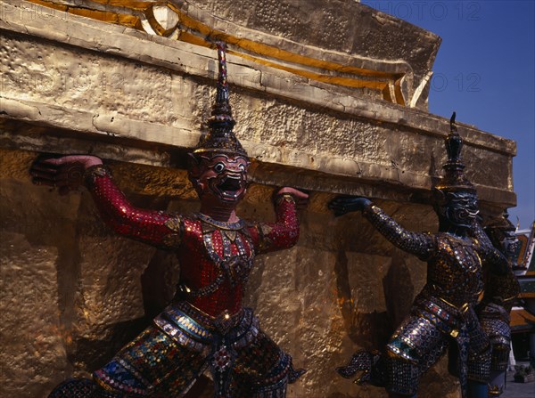 THAILAND, Bangkok, The Grand Palace.  Detail of figures encircling golden spire decorated with brightly coloured mosaic.