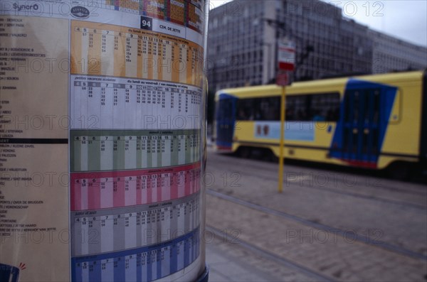 BELGIUM, Brabant, Brussels, Sign detailing tram times with passing tram beyond.