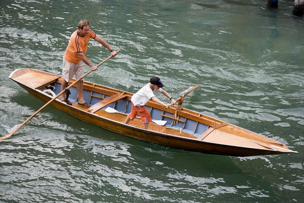 ITALY, Veneto, Venice, Man and young boy rowing a traditional boat in the gondola manner along the Grand Canal