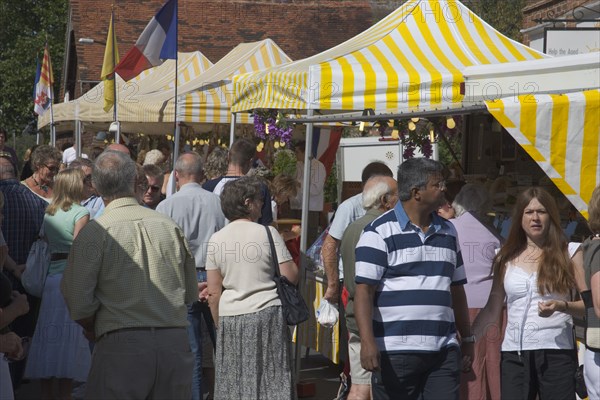 ENGLAND, West Sussex, Shoreham-by-Sea, French Market. People looking around yellow and white striped covered market stalls