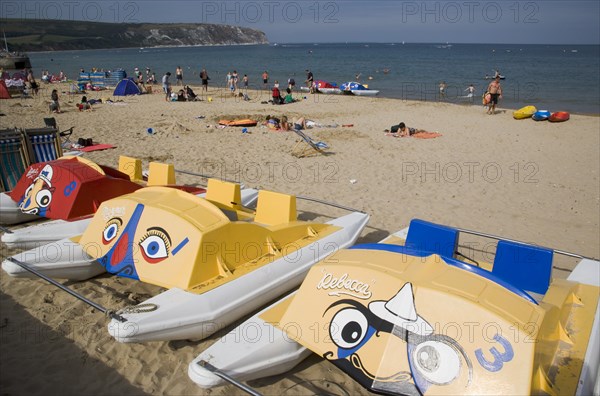 ENGLAND, Dorset, Swanage Bay, Colourful pedalo leisure boats painted with faces on sandy beach